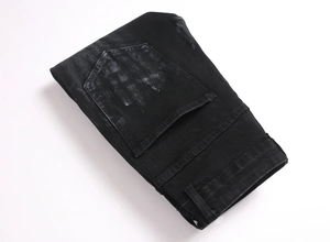 Detailed view of black denim jeans featuring distressed rear pocket and faded edges