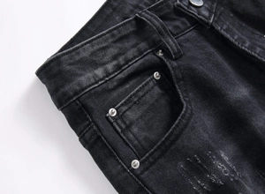 Dettaglio ravvicinato della tasca portamonete su jeans neri con rivetti lucidi