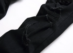 Detailaufnahme der Distressed-Ripped-Textur auf einer schwarzen Slim-Fit-Denim-Jeans