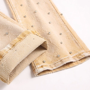 Schmal geschnittene gelbe Schlagjeans mit Strass-Rautenmustern und abgenutztem Saum
