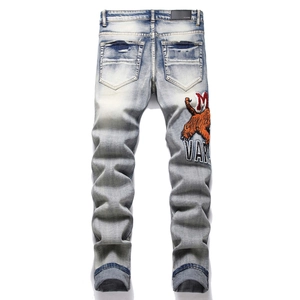 Detail of tiger embroidery and vintage distressed whiskers on light blue slim fit jeans