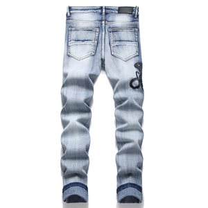 Detailansicht der schwarzen Schlangenstickerei und des Leder-Patches auf hellblauer Jeans