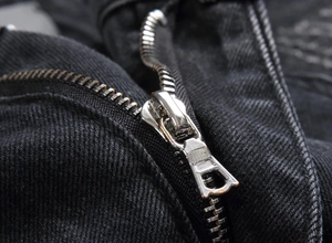 Dettaglio della cerniera in metallo argento sui pantaloni in denim nero