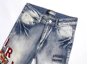 Detail of vintage blue jeans with tiger embroidery and distressed wash effects