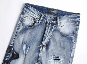 Detailaufnahme der hellblauen Jeans mit Cobra-Stickerei und modischen Distressed-Effekten