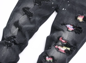Dettaglio di denim nero invecchiato con strass colorati e macchie di vernice bianca