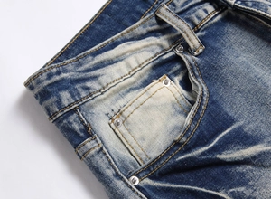 Detail of vintage blue stretch jeans with classic whiskers and orange stitching