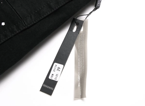 Close-up of black denim garment tags showing size 29 and premium metal hardware details