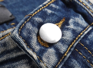 Macro detail of high-quality denim waistband with silver button and yellow topstitching