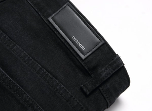 Detail des IXIAIMIRI Markenetiketts aus schwarzem Leder auf Stretch-Denim-Jeans