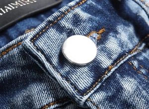 Nahaufnahme eines silbernen Metallknopfs und gewaschenem Denim bei blauen Stretchjeans