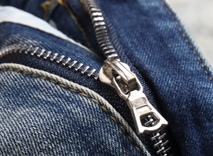 Detailed close-up of premium metal zipper and textured denim fabric on blue jeans
