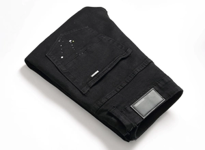 Detail of black stretch denim with paint splatters, leather patch, and metal logo tag