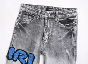 Detailed macro view of the grey washed denim jeans featuring blue 3D embroidered applique