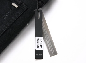 Detailaufnahme von schwarzem Denim mit Metalllogo und Papieretikett der modischen Jeans