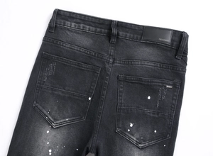 Dettaglio posteriore di jeans grigi usurati con schizzi di vernice e toppa in pelle in vita