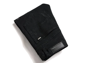 Detailaufnahme der schwarzen Jeans mit Leder-Markenpatch und Stickerei auf der Gesäßtasche