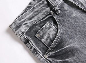 Detail of grey acid wash denim fabric with silver metal rivets and stitching on waistband