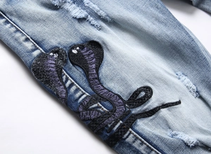 Detailaufnahme der Cobra-Stickerei auf hellblauer, destroyed Stretch-Jeans für Herren