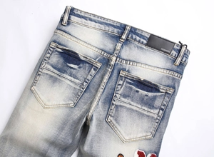 Close-up of light blue vintage jeans featuring tiger embroidery and distressed details