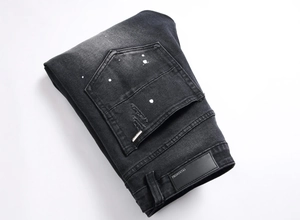 Dettaglio di jeans nero antracite con schizzi di vernice bianca e tasca dall'effetto usurato