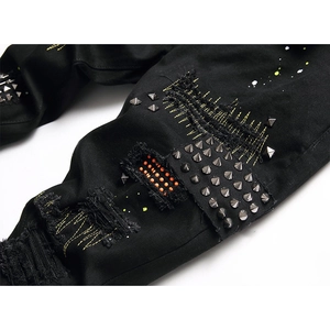 Men's black distressed skinny jeans with silver spikes, metal studs, and yellow embroidery
