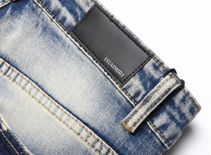Detail of blue wash denim waist with black IXIAIMIRI leather patch and orange stitching