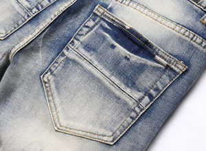 Macro view of blue denim jeans with metal logo plate and contrast yellow stitching