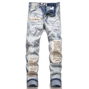 Men's light blue distressed skinny jeans with graffiti patches and ripped details