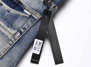 Detail of blue jeans featuring tiger embroidery, logo metal tag, and white size labels