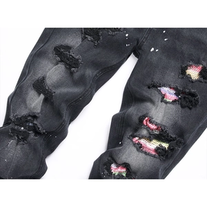Jeans neri distressed con toppe multicolore e schizzi di vernice bianca stile streetwear