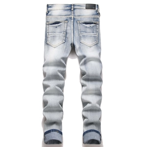 Close-up of blue slim fit jeans featuring branded leather patch and washed denim texture
