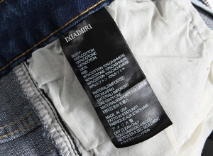 Detail of product care label on blue denim showing 100% cotton material and brand info