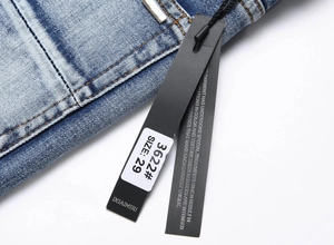 Makroansicht hellblauer Jeans mit Details zu Nähten, Metallknopf und Produktetiketten