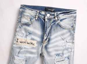 Detailed view of blue distressed jeans with embroidery patches and heavy wash effects