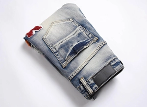 Detail of vintage blue jeans featuring tiger head embroidery and a black leather brand patch