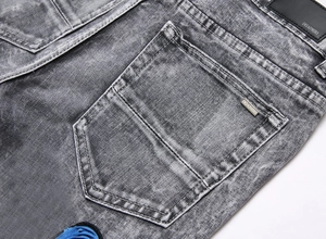 Detailed macro view of the branded metal plaque and leather patch on grey washed jeans