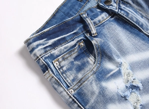 Détails de la taille d'un jean bleu avec rivets métalliques et bords usés par l'usure