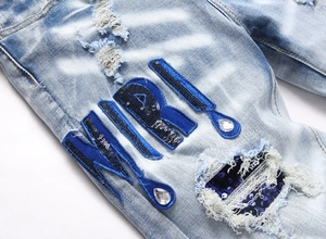 Détail de jean bleu clair délavé avec écussons à paillettes et accents de strass