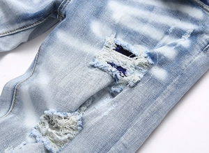 Détails de denim vieilli avec déchirures et empiècements sur un jean bleu clair