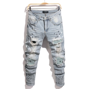 Detail of blue distressed skinny jeans with paint splatters and textured knee patches