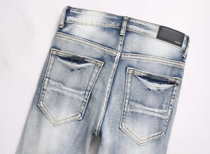 Close-up of black leather brand patch on light blue washed distressed denim jeans