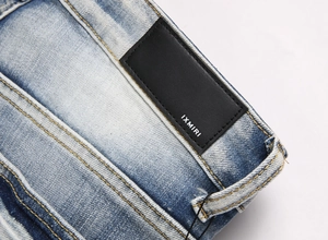 Close-up of blue washed denim texture and black leather brand patch with fine stitching