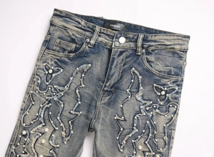 Détail du jean évasé bleu avec broderie ondulée et ornements en perles blanches