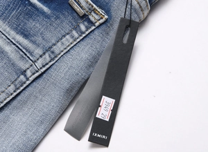 Détail macro du tissu denim bleu avec délavage moustaches et plaque de logo argentée