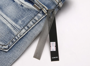 Close-up of blue distressed denim jeans showing waist stitching and brand labels