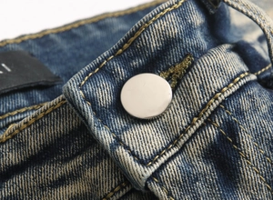 Détail du denim bleu délavé avec bouton en métal et surpiqûres jaunes contrastées