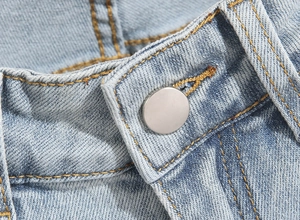 Detailed close-up of a silver metal button and tan stitching on blue denim jeans