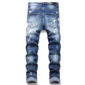 Detail view of high street blue denim jeans with splattered paint and distressed embroidery