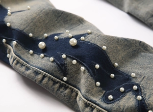 Gros plan d'un jean évasé bleu avec patchwork et broderie détaillée de perles blanches